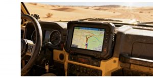 Off-road vehicle dashboard with a sunlight-readable GPS screen visible under bright desert conditions.